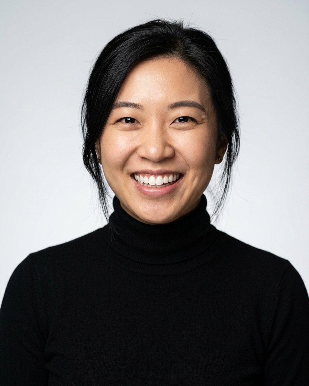 Light grey studio headshot, black turtleneck